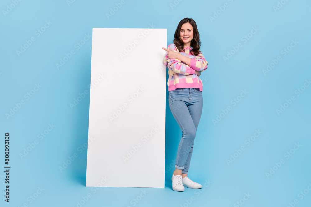 Full length photo of young lady indicate finger empty space select suggest proposition isolated over blue color background Full length photo of young lady indicate finger empty space select suggest proposition isolated over blue color background