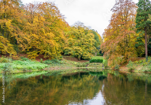 Autumn landscape with river and colorful trees in the city park.