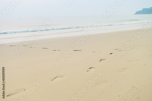 Footprints of human feet on the sand near the water on the beach.