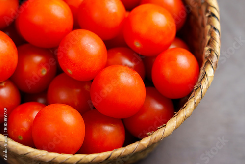 Organic small red cherry tomatoes in a rustic wicker bowl