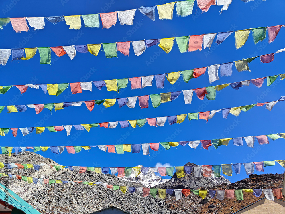 Tibetan prayer flags flutter against a clear blue sky, high in the Himalayas