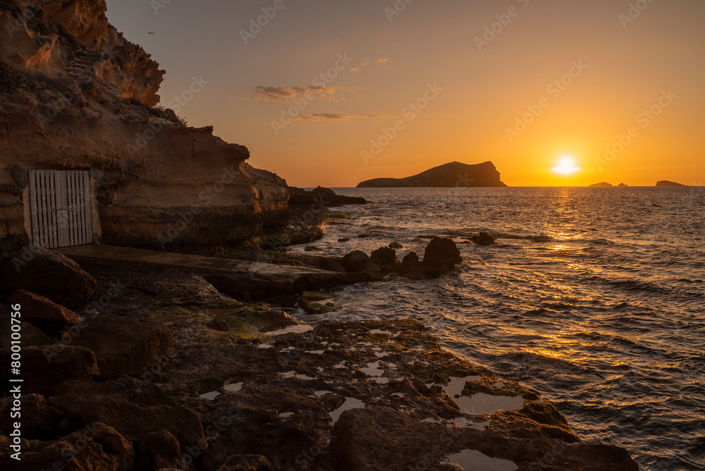 Fishing huts in the sandstone cliff and the sunset view at cala Comte beach, Sant Josep de Sa TalBeautifuaia,  Ibiza, Balearic Islands, Spain