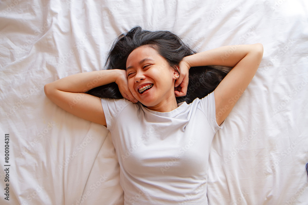 Top view of happy asian young woman lying in bed Top view of happy asian young woman lying in bed