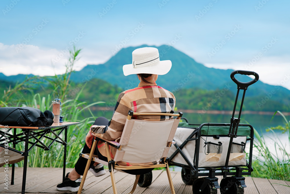 A woman is sitting on a chair and enjoying the beautiful lake and mountain scenery. A woman is sitting on a chair and enjoying the beautiful lake and mountain scenery.
