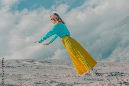 Woman wearing yellow skirt balancing on toes under cloudy sky