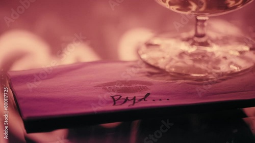 Bye message and lipstick mark on a napkin under a glass