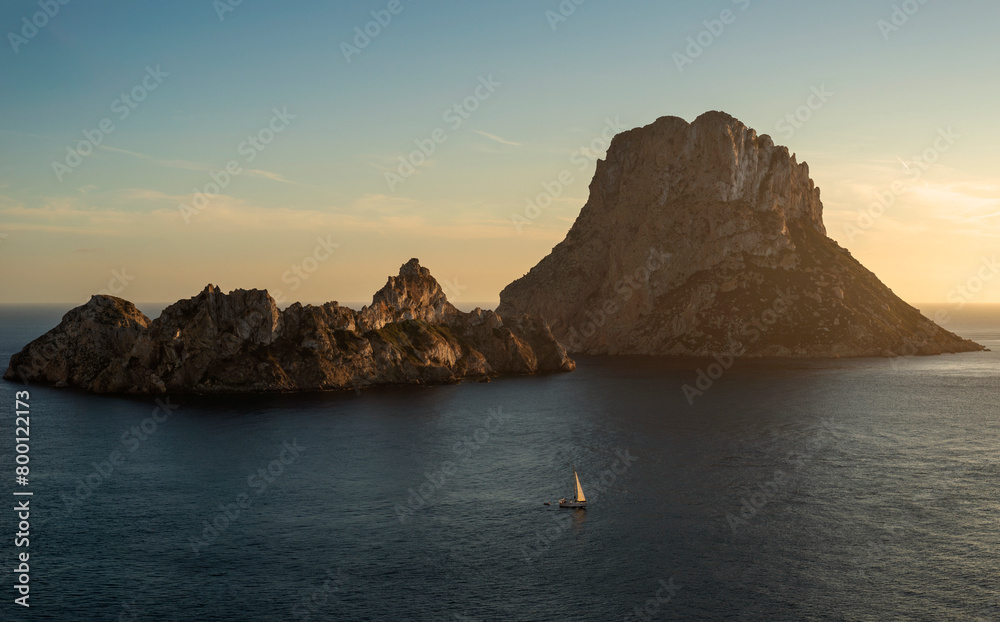 Naklejka premium Sailboat sailing around Es Vedra and Es Vendrell at sunset panoramic view, Sant Josep de Sa Talaia, Ibiza, Balearic Islands, Spain