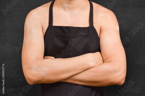 The torso of a male chef in an apron on a black background. Cooking concept