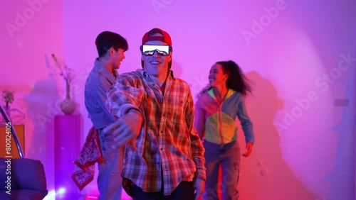 Happy hipster wear fancy glasses dancing while looking at camera at studio with neon light. Funny happy dancing team moving to hip hop rhyme or modern pop beat with caucasian performer. Regalement. photo