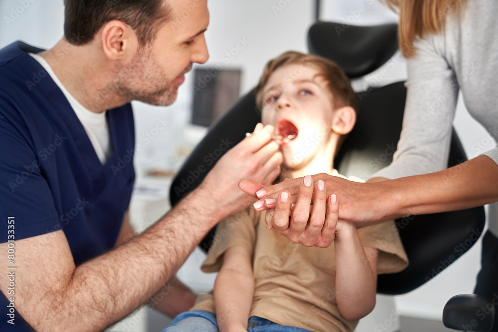 Fototapeta premium Mother supporting son having visit at dentist