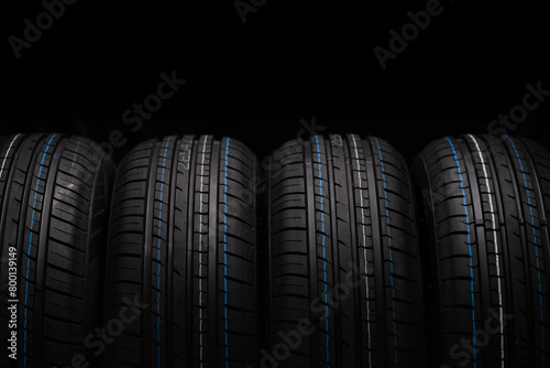 Car tires stacked in a row isolated on black background, closeup. photo