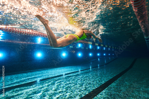 a beautiful young athletic girl in a yellow swimsuit and swimming goggles swims in a sports pool. underwater photography
