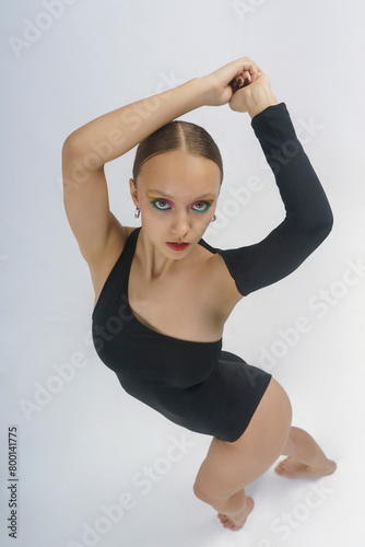young female dancer in a bodysuit shows elements of choreography with her hands above her head top view © Alex