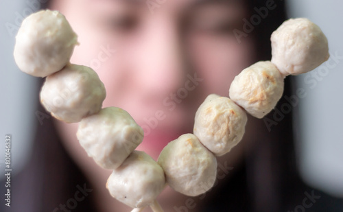 Woman happily eating meatball on blurred background