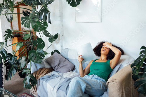 Cute mixed race girl is lying on the sofa and suffering from the summer heat.