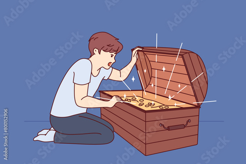 Little boy has found treasure with gold coins and joyfully opens mouth seeing contents of chest. Child dreams of finding treasure trove of pirate treasures during trip to mysterious island.