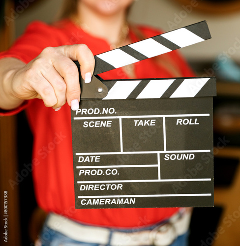 Woman's hands holding a clapperboard. A young girl holding a movie clapboard in front of a red  background.