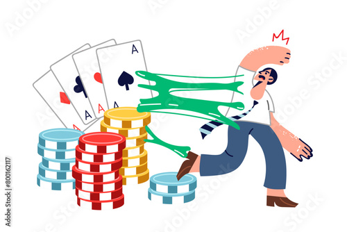 Man suffering from gambling addiction trying to escape from large playing cards and casino chips