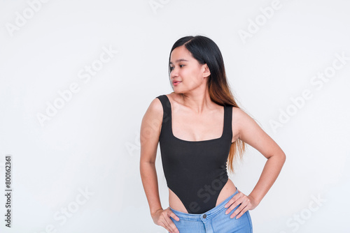 Confident young Asian woman in black bodysuit posing on white background