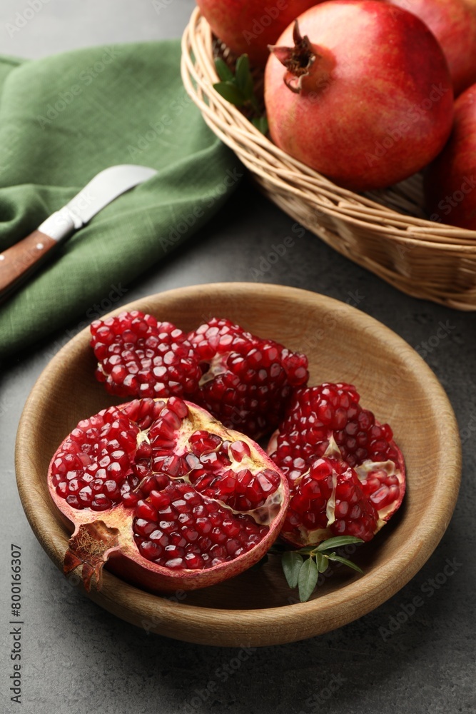 Fresh pomegranates, green leaves and knife on grey table Fresh pomegranates, green leaves and knife on grey table