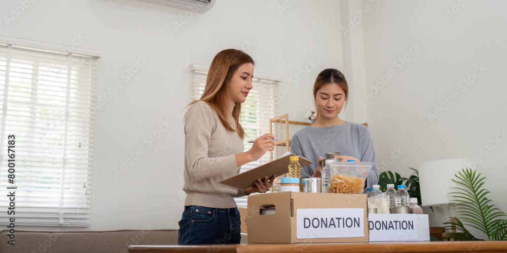 Donation and two woman volunteer asian of happy packing food in box at home. Charity Donation and two woman volunteer asian of happy packing food in box at home. Charity
