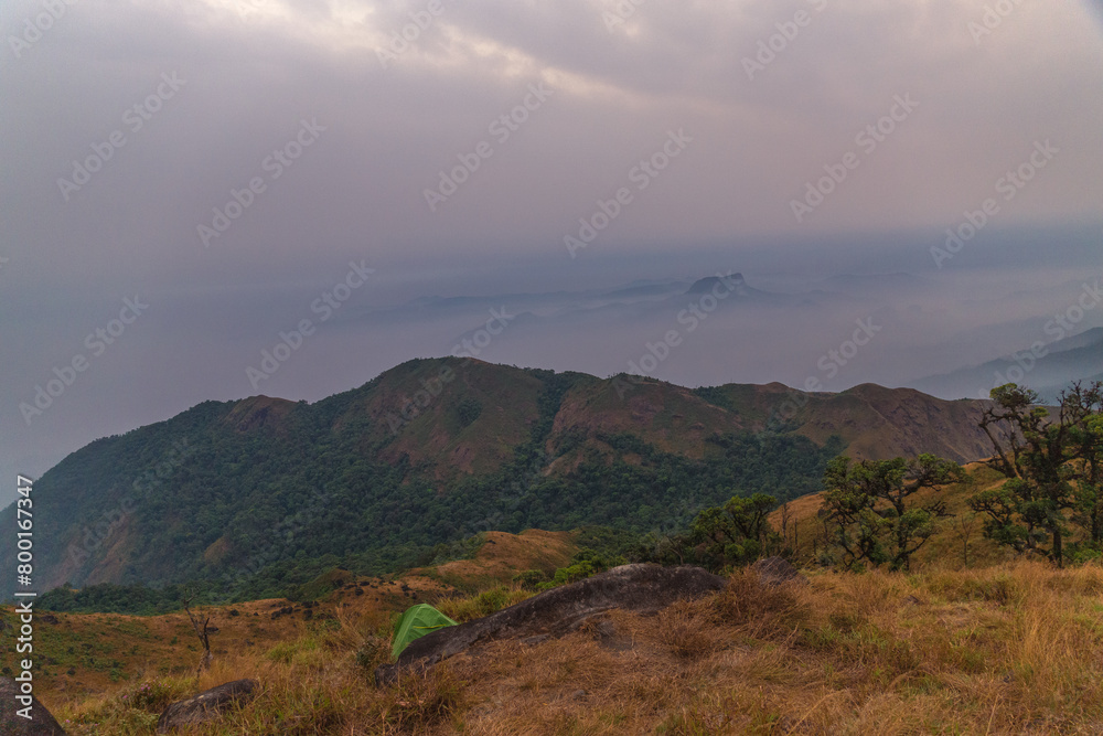 A mountain range with a green tent on top A mountain range with a green tent on top
