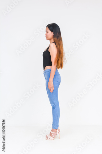 Young Asian woman in a sleek black bodysuit and blue jeans posing on white background