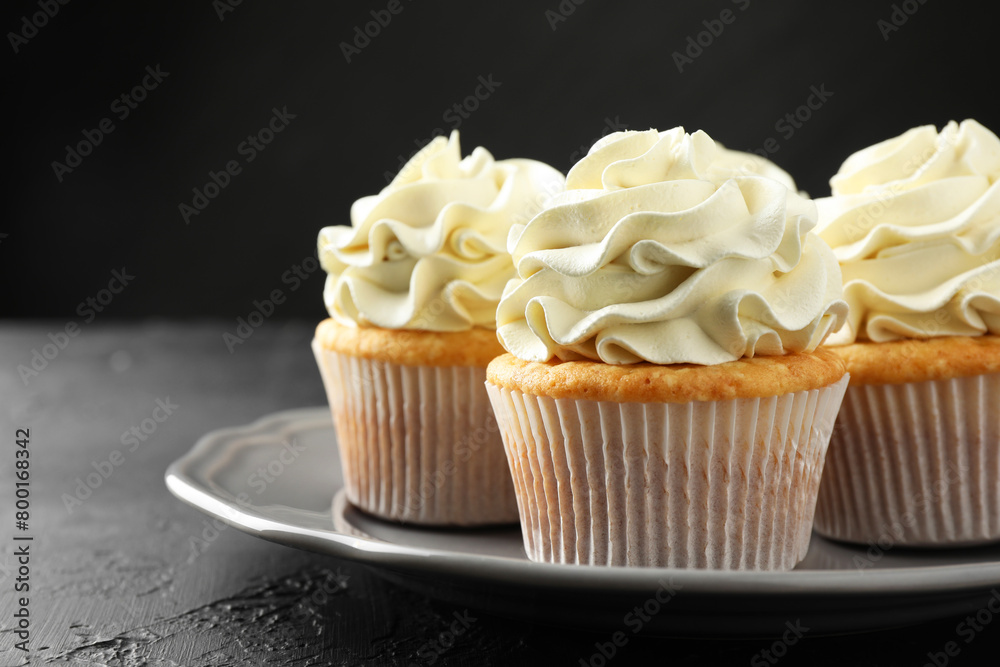 Tasty cupcakes with vanilla cream on black table, closeup Tasty cupcakes with vanilla cream on black table, closeup