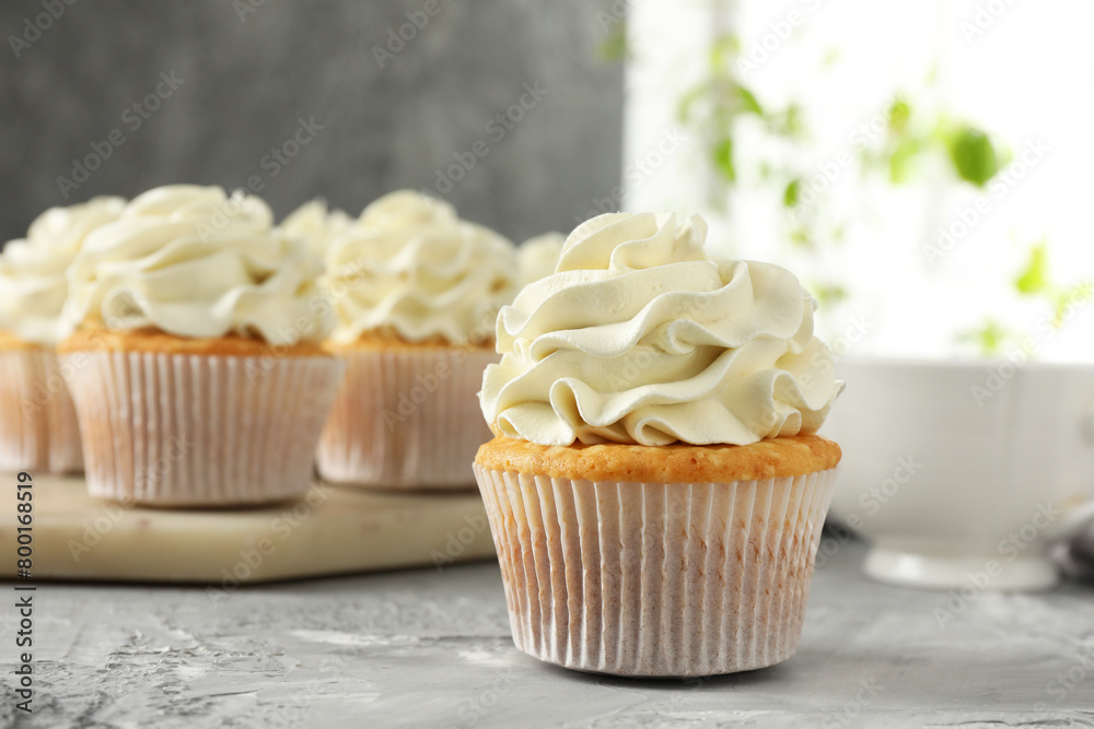Tasty cupcakes with vanilla cream on grey table, closeup Tasty cupcakes with vanilla cream on grey table, closeup
