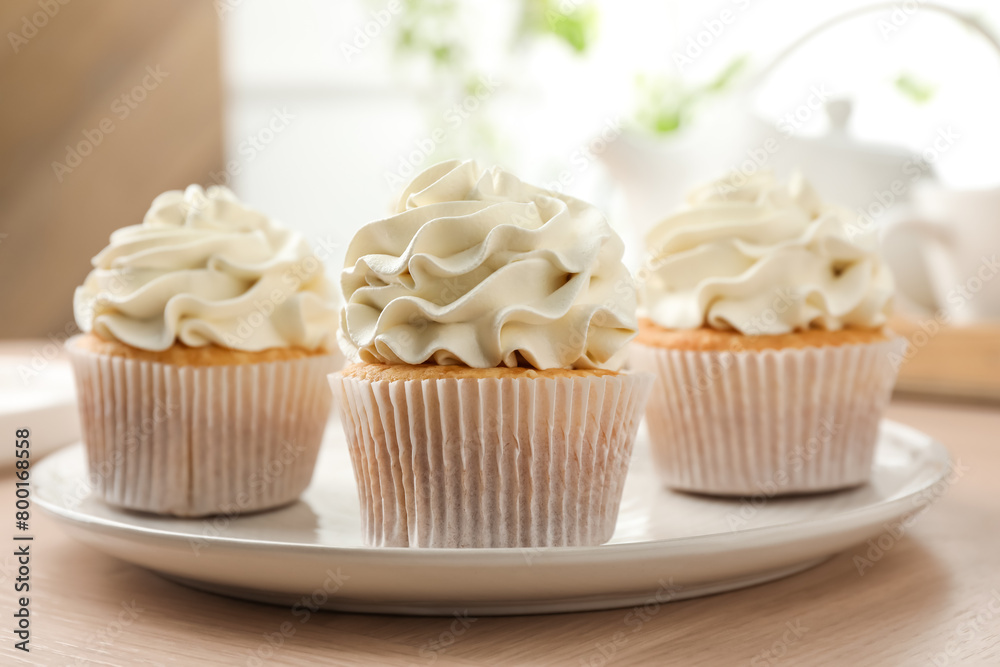 Tasty cupcakes with vanilla cream on light wooden table, closeup Tasty cupcakes with vanilla cream on light wooden table, closeup