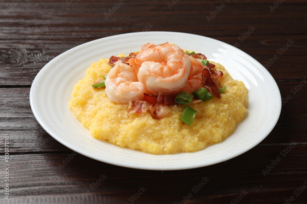 Plate with fresh tasty shrimps, bacon, grits and green onion on dark wooden table Plate with fresh tasty shrimps, bacon, grits and green onion on dark wooden table