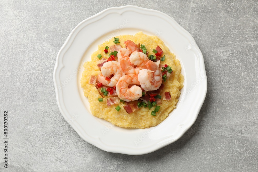 Plate with fresh tasty shrimps, bacon, grits, green onion and pepper on gray textured table, top view Plate with fresh tasty shrimps, bacon, grits, green onion and pepper on gray textured table, top view
