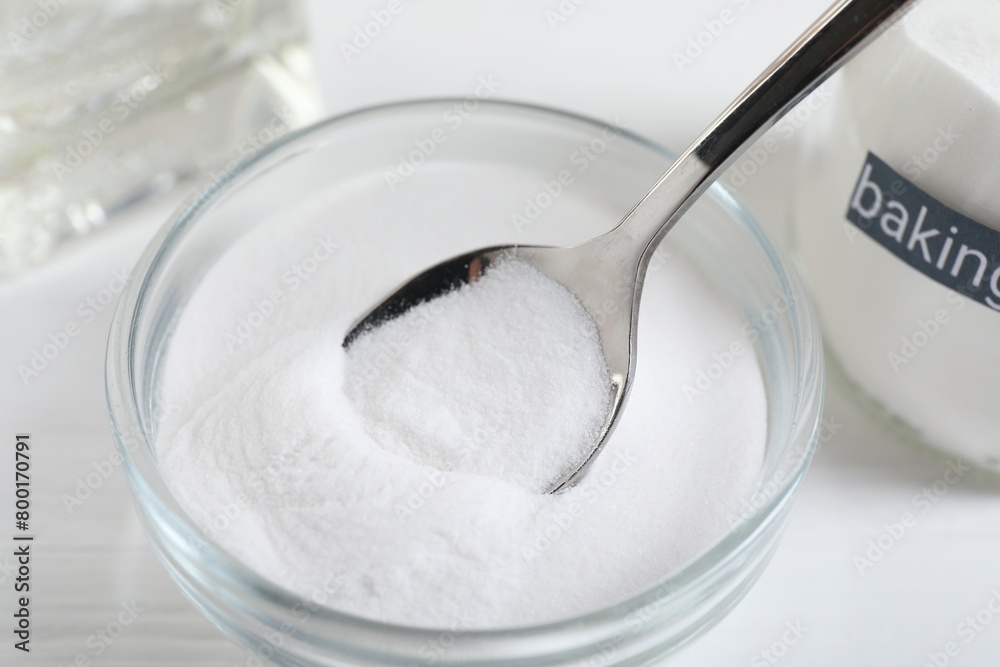 Taking baking soda from bowl at white wooden table, closeup Taking baking soda from bowl at white wooden table, closeup