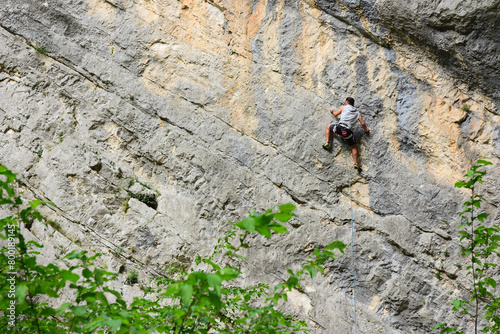 uomo si arrampica su una grande parete rocciosa in montagna, scalata estrema difficile, sport estremo photo