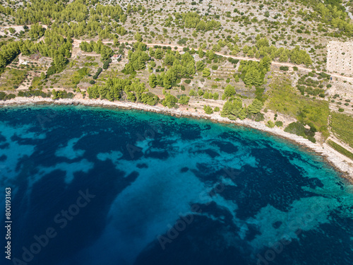 AERIAL: Stunning turquoise sea reaches rocky shoreline of Mediterranean island photo