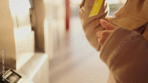 A woman's hand is shown inserting a yellow transport card into a recharge machine, a daily commuting routine. photo