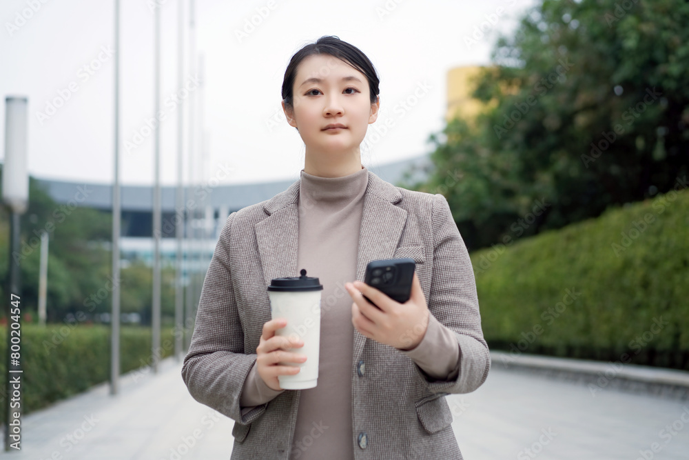 Modern Professional Woman Balancing Work and Coffee Outdoors