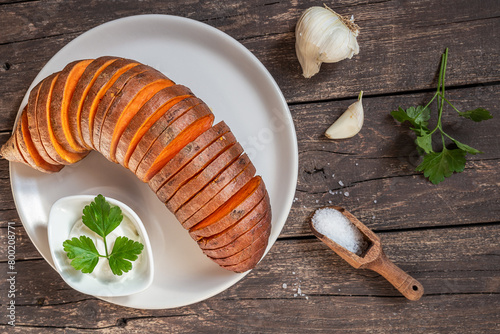 Roasted hasselback sweet potatoes with spices on a wooden table