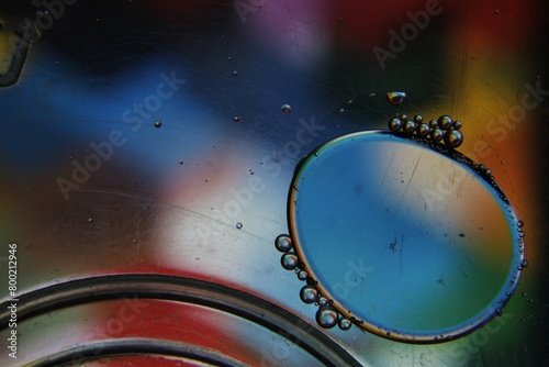 Burbujas de agua y aceite flotan en la superficie líquida, forman esferas grandes y pequeñas coloridas por refracción, original diseño abstracto para fondos.