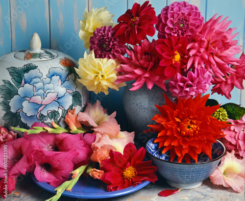 Fotografia still life of dahlias and gladioli in a vase on a marble table with blue painted background