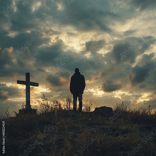 A man praying in front of a crucifix under a dramatic cloudy sky.