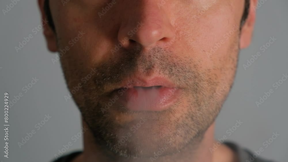 Close-up of a man smoking an electronic cigarette and exhaling smoke. Close-up of a man smoking an electronic cigarette and exhaling smoke.
