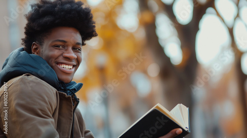 Jovem homem universitário feliz lendo um livro no Campus da universidade