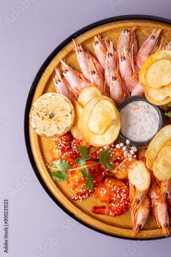 Top view of wooden plate with assorted seafood and sauces