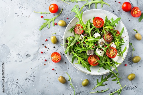 Healthy and tasty vegetarian salad with chia seeds arugula tomatoes cheese and olives on concrete background photo