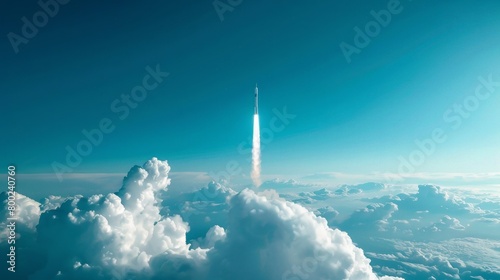 A rocket ascends through a clear blue sky, leaving a contrail as it pierces through white, fluffy clouds, symbolizing human technological advancement and exploration. photo