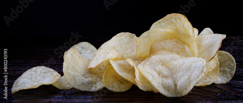Potato chips on a dark background. Chips on a wooden board