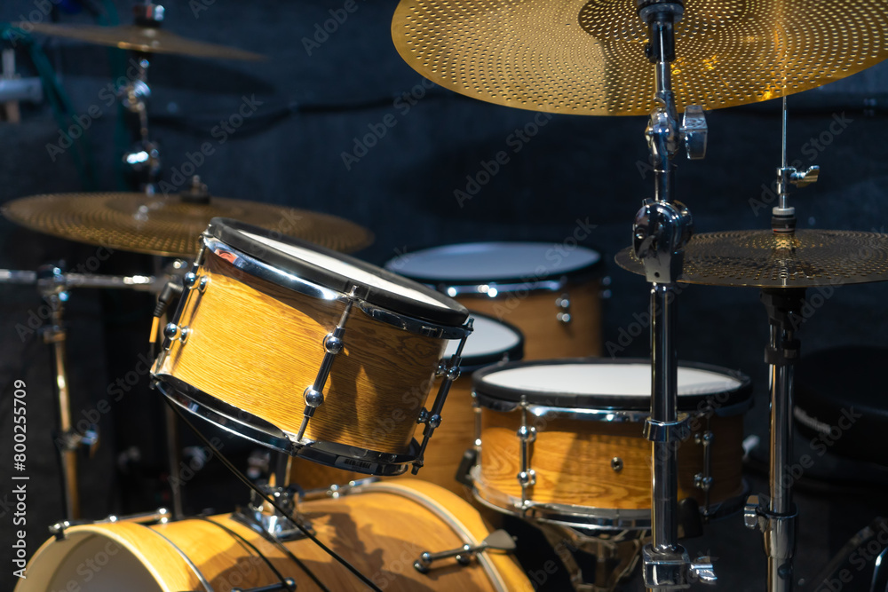 Close-up of a fragment of a drum kit matching the color of a tree in the studio, selective focus Close-up of a fragment of a drum kit matching the color of a tree in the studio, selective focus