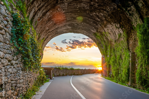 Beautiful road in a rock tunnel with amazing sunset. Road near the lake