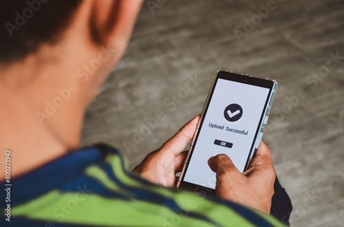 Man finished uploading files online on his mobile phone. Selective focus, concept of file upload vulnerabilities, attacks.  photo